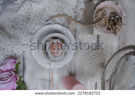 Still life photography with the concept of victorian style, with a composition of mirror, cups, candles and pearl necklaces
