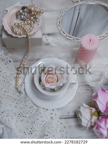 Still life photography with the concept of victorian style, with a composition of mirror, cups, candles and pearl necklaces
