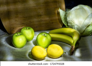 Still life photography and green apples  lemons  cabbage  bananas   wooden desk at the canvas tablecloth and black background   light shadow drawing in the dark 