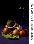 Still life with pumpkin, apples, grapefruits, bananas and a vase of flowers with a camelia bud