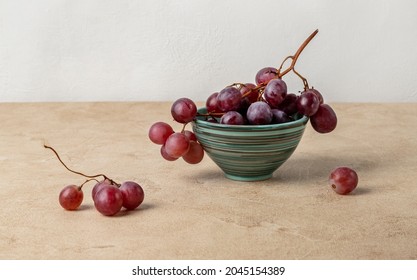 Still life with red grapes lying in a ceramic bowl. Beige textured background, horizontal orientation. - Shutterstock ID 2045154389