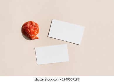 Still Life Scene With Red Shell On Beige Background In Sunlight And Blank Business, Greeting Card, Invitation Mockup. Long Harsh Shadows. Flat Lay, Top View.