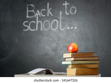 Still life with school books and apple against blackboard with "back to school" on background - Powered by Shutterstock