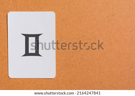 Still life shot of a white card, with a zodiac sign printed on it, specifically the sign of Gemini