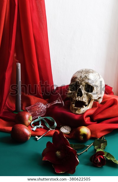Still Life with Skull in the style of\
vanitas with vintage retouching. Skull, glass, candle, keys,\
watches, apple, flower on a background of red\
drapes.