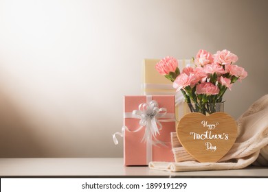 Still Life With Sweet Carnation Flowers And Gift On Table, Mothers Day Concept