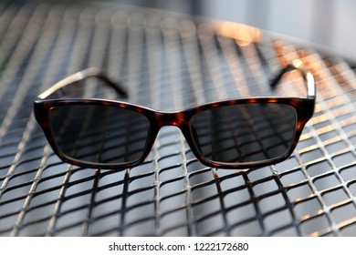 Still Life Of Tortoise Shell Glasses On An Outdoor Iron Mesh Table Showing Depth Of Field.