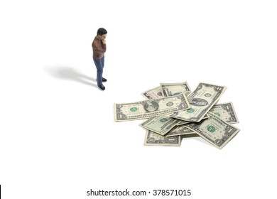 Still Life Of A Toy Person Standing Next To A Pile Of Money On A White Background