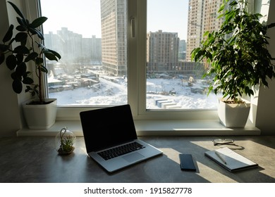 Still Life View Of Office Room With Open Laptop Computer On Desk With Reflections By Bright Window, Office Interior. Professional Workplace Technology Indoors.