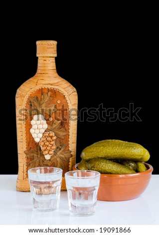 Still life with vodka and cucumbers at the black background
