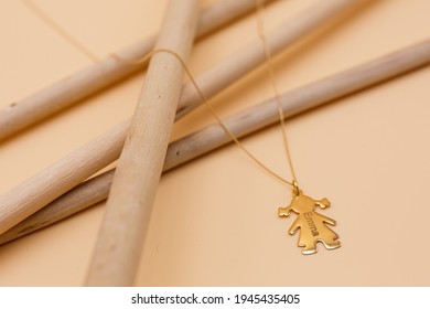 Still Life Of A Woman's Gold Necklace With A Doll-shaped Pendant Engraved With The Name