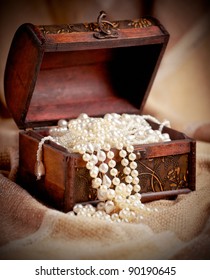 Still life with wooden treasure chest with pearl necklaces.