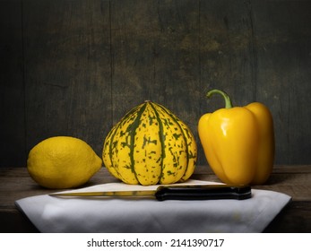 Still life with yellow lemon, squash, bellpepper and knife chiaroscuro style. Fate, destiny, life and death concept.