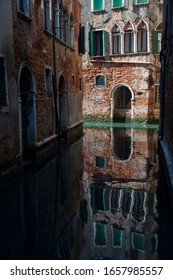 Still Scenic View Of Quiet Canal With An Arched Entrance At Water Level In Venice, Italy