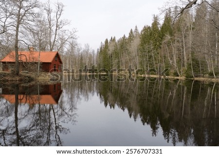 Still water reflection in water with tree line and red house