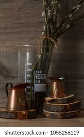 Still-life. Kitchen interior. copper measuring cups on wooden circles with willow branches on a wooden table. On brown wooden background. Spring