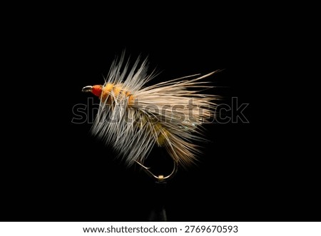 Stimulator Dry Fly A close-up studio shot of a Stimulator fly fishing lure against a black background. Featuring a yellow body, orange head, and buoyant dee hair wing, this pattern is a classic.
