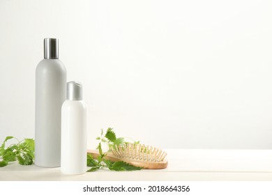 Stinging Nettle, Cosmetic Products And Brush On White Wooden Background, Space For Text. Natural Hair Care