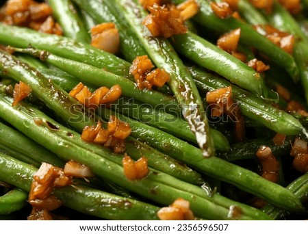 Stir fried garlic, ginger green beans in black bowl