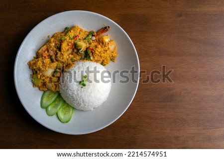 Stir Fried Prawns with Curry Powder on a wooden table, Stir Fried Shrimp with curry powder with fried egg rice, Thai food thai cuisine food on dish, Copy space.