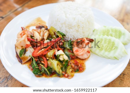 Stir fried seafood squid shrimp prawn with holy basil and rice / Thai food spicy fried recipe with cucumber and chili 