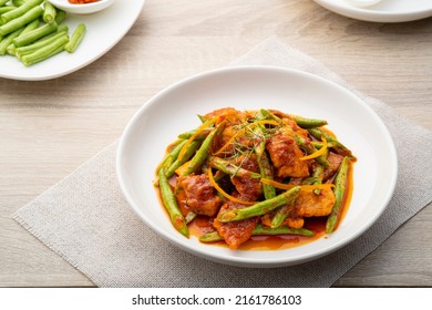 Stir fried sliced pork and red curry paste with sting bean in white plate,pad prik gaeng