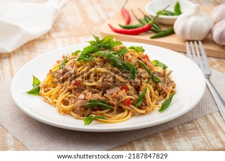 Stir fried Spaghetti with Canned tuna fish and crispy basil leaves in white plate,Spicy pasta Pad Kra Pao.Thai fusion food