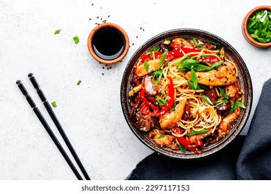 Stir fry noodles with chicken, red paprika, mushrooms, chives and sesame seeds in bowl. Asian cuisine dish. White table background, top view