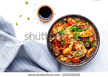 Stir fry noodles with chicken slices, red paprika, mushrooms, chives, soy sauce and sesame seeds in ceramic bowl. Asian cuisine dish. White table background, top view