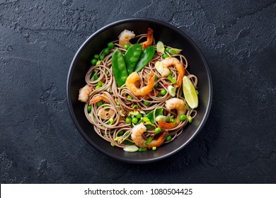 Stir Fry Noodles With Vegetables And Shrimps In Black Bowl. Slate Background. Top View.