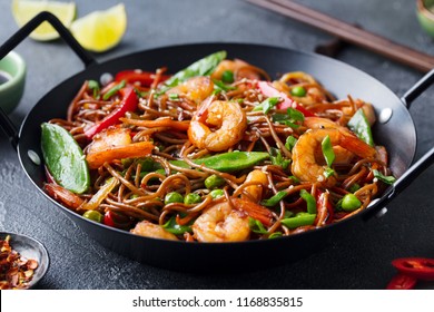 Stir fry noodles with vegetables and shrimps in black iron pan. Slate background. Close up. - Powered by Shutterstock