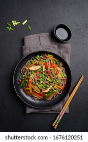 Stir fry noodles with vegetables and soy sauce. Asian food background. Black stone background - Shutterstock ID 1676120251
