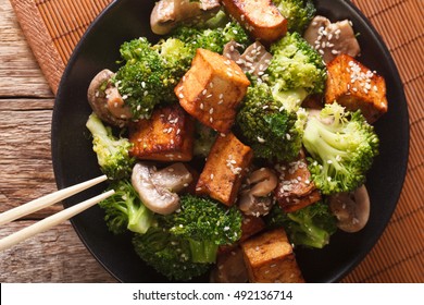 Stir Fry Of Tofu, Broccoli, Mushrooms And Sesame Close-up On A Plate. Horizontal View From Above
