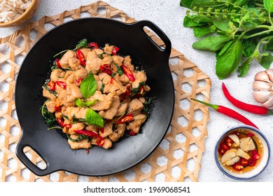 Stir-fried basil with chicken in the black plate (wok looks), top view of Thai local cuisine food