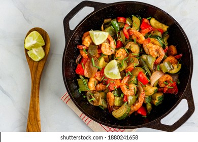 Stir-Fried Shrimp With Vegetables In A Cast Iron Wok Garnished With Garlic Chives And Lemon Top Down Photo