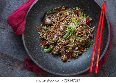 Stir-fried Soba Noodles With Beef Meat In A Wok Pan, Above View On A Grey Asphalt Background, Studio Shot