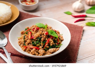 Stir-fried Thai basil with pork which   famous Thai food is hot and spicy dish  serving with rice and fish sauce on a wooden table