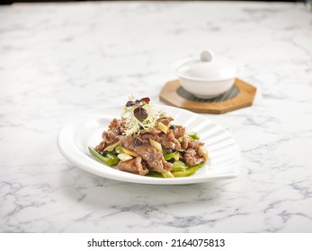 Stir-fried US Angus Beef With Bitter Gourd In Black Bean Sauce Served In A Plate Side View On Grey Marble Background USA Food