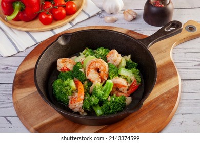 Stir-fry broccoli and shrimp in a pan, on the table.