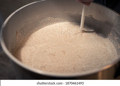 Stirring Mash In Big Stainless Steel Keg During Process Of Brewing Beer At Home In Garage