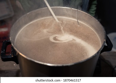 Stirring Mash In Big Stainless Steel Keg During Process Of Brewing Beer At Home In Garage