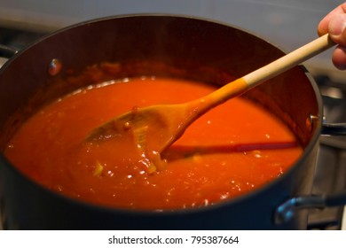 Stirring A Pot Of Hot Tomato Soup With A Wooden Spoon.