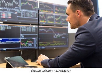 Stock Broker Trading Online While Accepting Orders By Phone. Trader's Office With Multiple Computer Screens Full Of Index Charts And Data Analyses