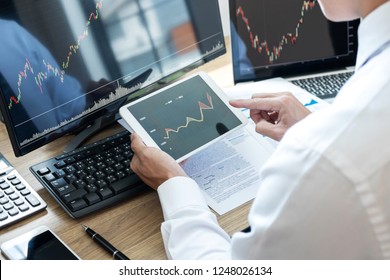 Stock exchange market concept, stock broker looking at graph working and analyzing with display screen, pointing on the data presented and deal on a exchange, Businessman trading stocks online. - Shutterstock ID 1248026134