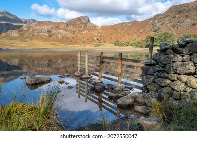 Stock fence and wall at Blea Tarn in Cumbria with reflections on the tarn.