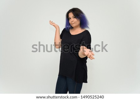 Stock Foto Portrait of a knee-deep funny cheerful girl of a young woman with multi-colored hair in a black T-shirt on a white background. In the studio, smiling, talking.