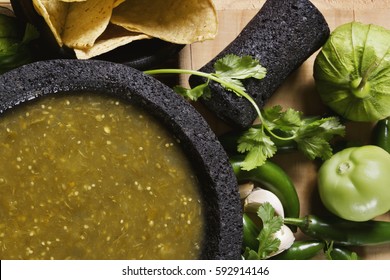 Stock image of mexican salsa verde on mortar and pestle with ingredients