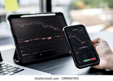 Stock investors hold a phone, open a stock chart viewer to read stock price charts, analyze purchases. Cryptocurrency stocks are popular with both new and old investors. investing in stocks. - Shutterstock ID 1989047492