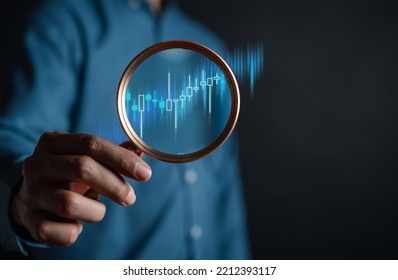 stock market for analysis technical grap. Businessman hand holding magnifier glass with virtual stock market chart, Business investment earning income concept.