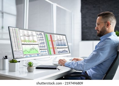 Stock Market Analyst At Office Desk Using Multiple Screens